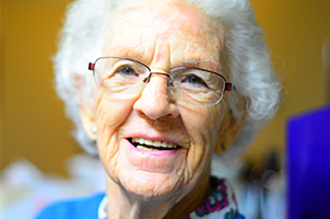 Dot grandmother with glasses and blue jumper smiling at camera widget.jpg